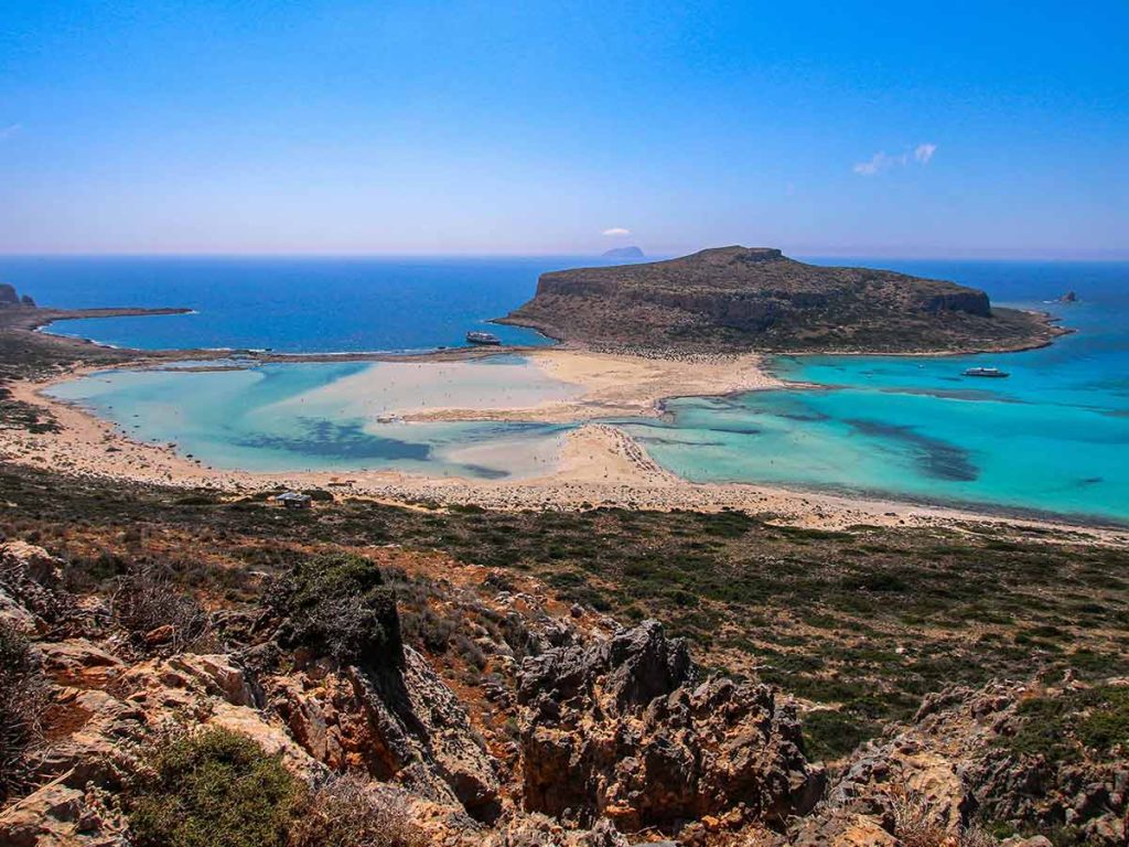 Panoramic view of Balos Lagoon in Crete, Greece, with turquoise waters, sandy shores, and rocky landscape.