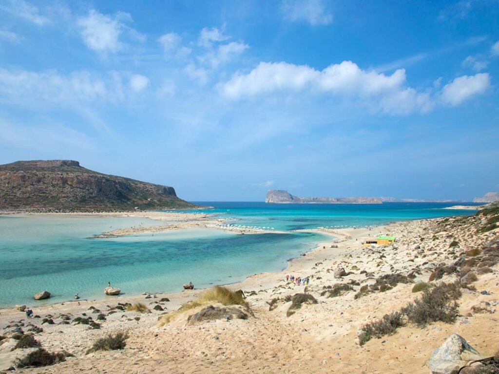 Scenic view of Balos Lagoon in Crete with turquoise waters, sandy beach, and distant cliffs under a clear blue sky – perfect cruise destination.