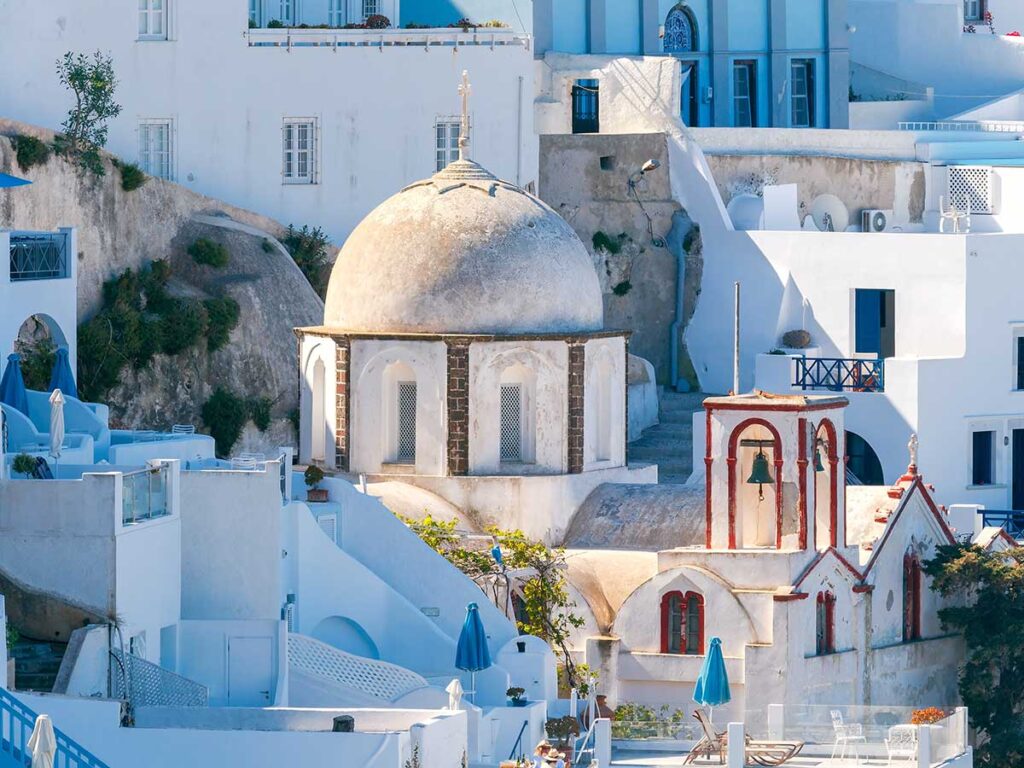 Traditional Cycladic church with a dome and bell tower among whitewashed houses