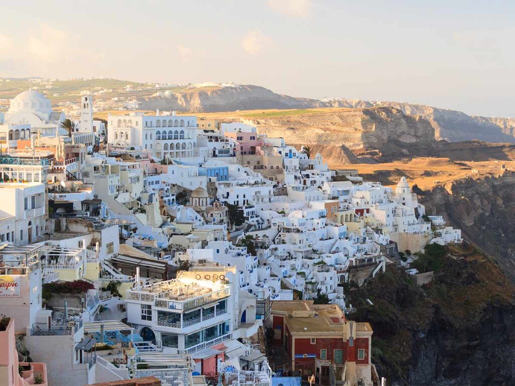 View of Oia town built on the cliffs with whitewashed buildings and volcanic backdrop