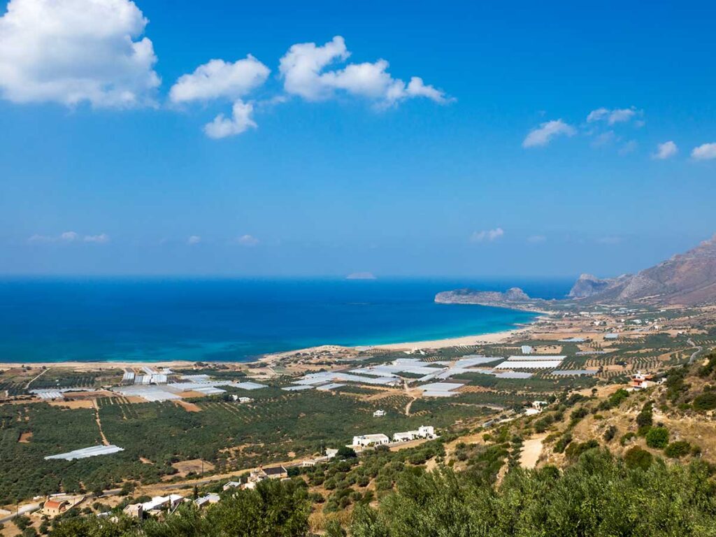 <strong>Crete temperature by month: What to expect all year round</strong> 4 Panoramic view of the Falassarna coast in western Crete, featuring farmland, greenhouses, turquoise sea, and hillsides under blue skies.