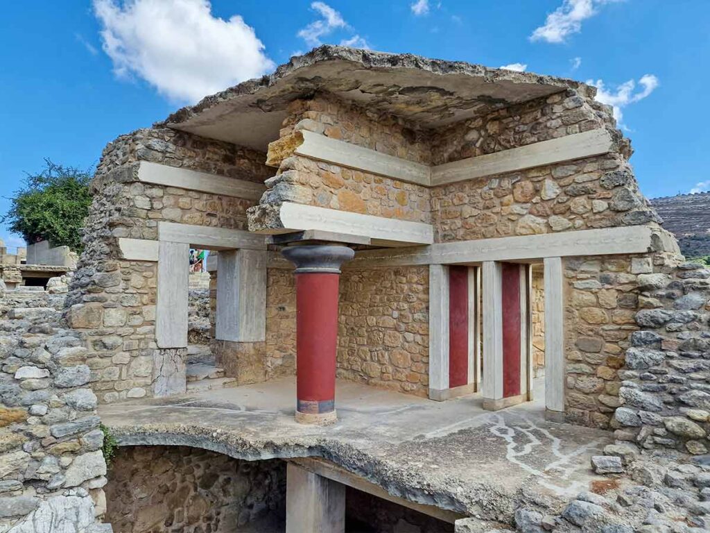 <strong>Planning your Knossos Palace tour: Must-see highlights and tips</strong> 4 A two-story section of the Knossos Palace showcasing lower levels, stone masonry, and a central red column.